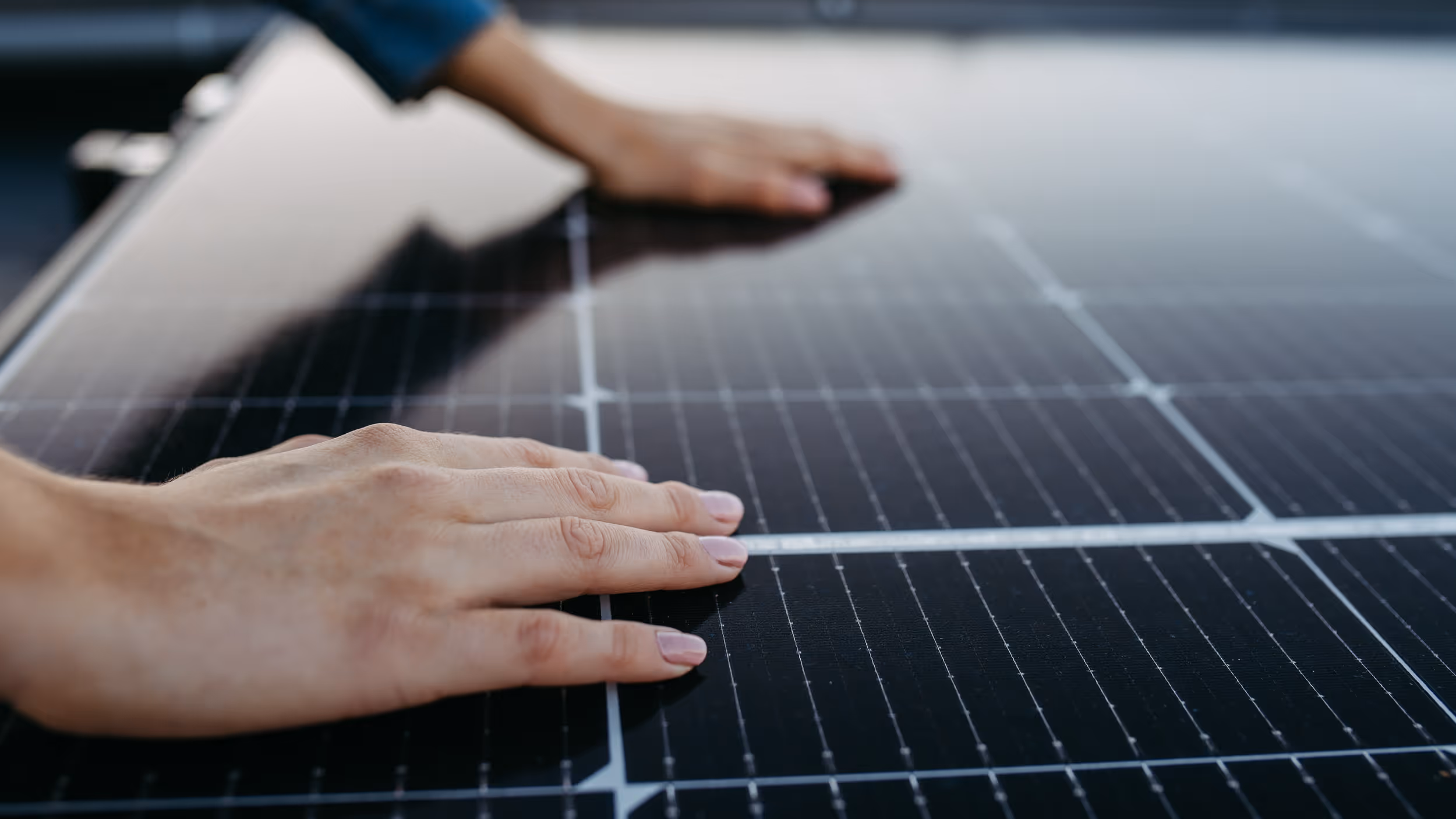 Person berührt vorsichtig die Oberfläche von Solarpanelen.