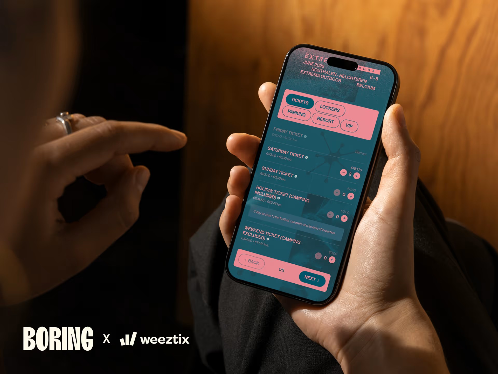 Person holding a smartphone displaying ticket selection options for a June 2025 outdoor festival in Belgium with categories like tickets, lockers, parking, resort, and VIP.