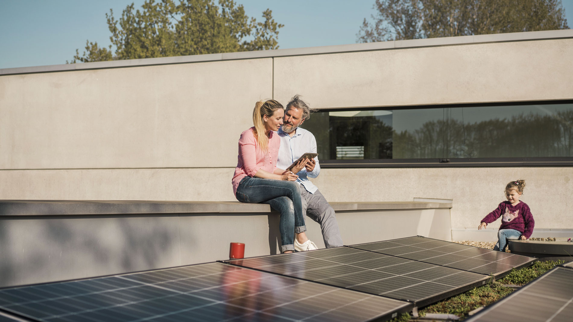 Familie antspannt auf Dachterrasse, mit PV-Anlage.