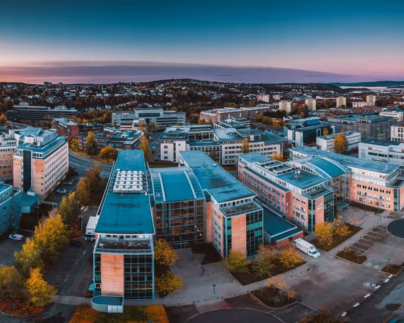 Aerial view of a modern urban area with large office and residential buildings under a twilight sky.