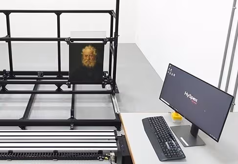 High-tech scanning device capturing an image of a classical portrait with a monitor and keyboard nearby.