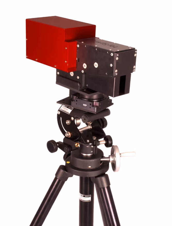 Close-up of a black and red scientific instrument mounted on a black tripod with adjustment knobs.