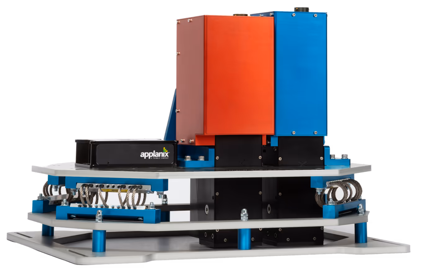 Technical device with red and blue rectangular units mounted on a multi-layered metal frame with coils and labeled 'applanix'.