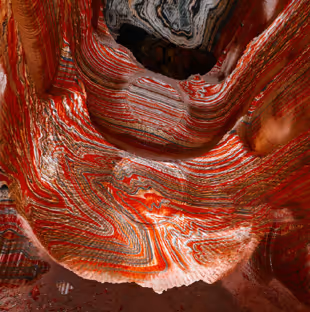 Close-up of red and white layered mineral formations with swirling patterns.