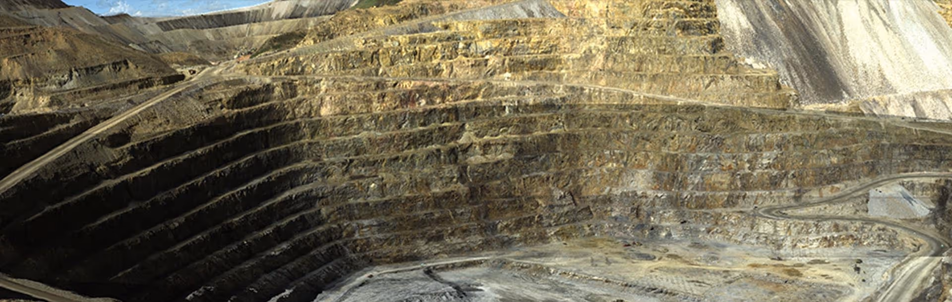 Wide aerial view of a terraced open-pit mine with multiple stepped levels and winding access roads.