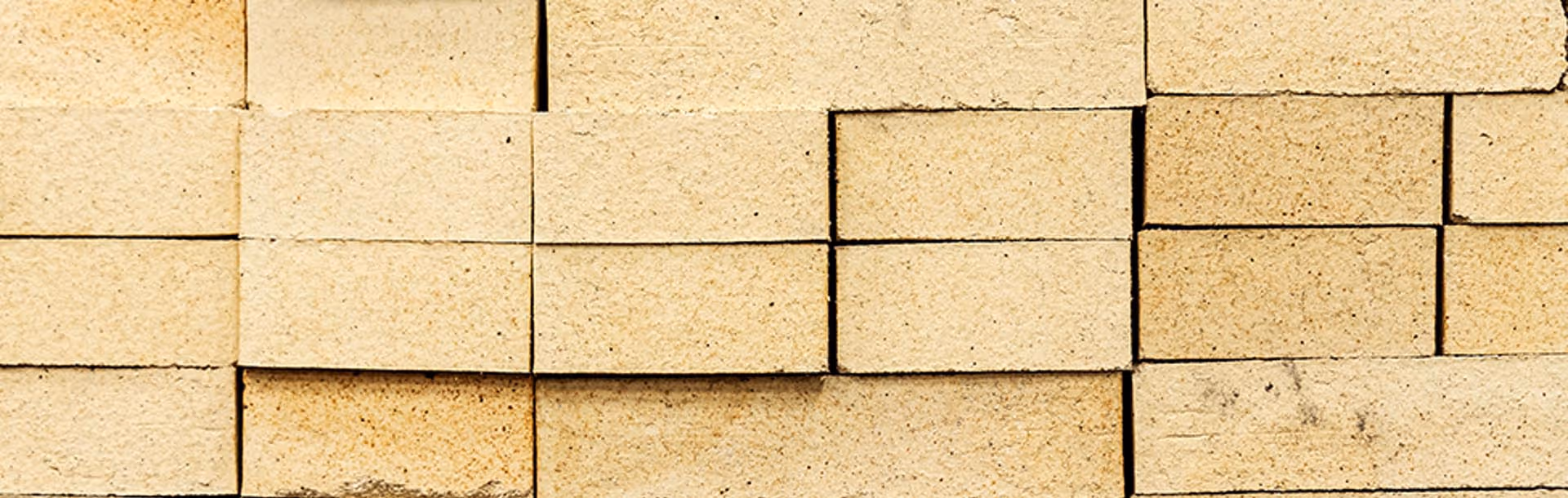 Close-up of a beige brick wall with rectangular bricks arranged in a staggered pattern.