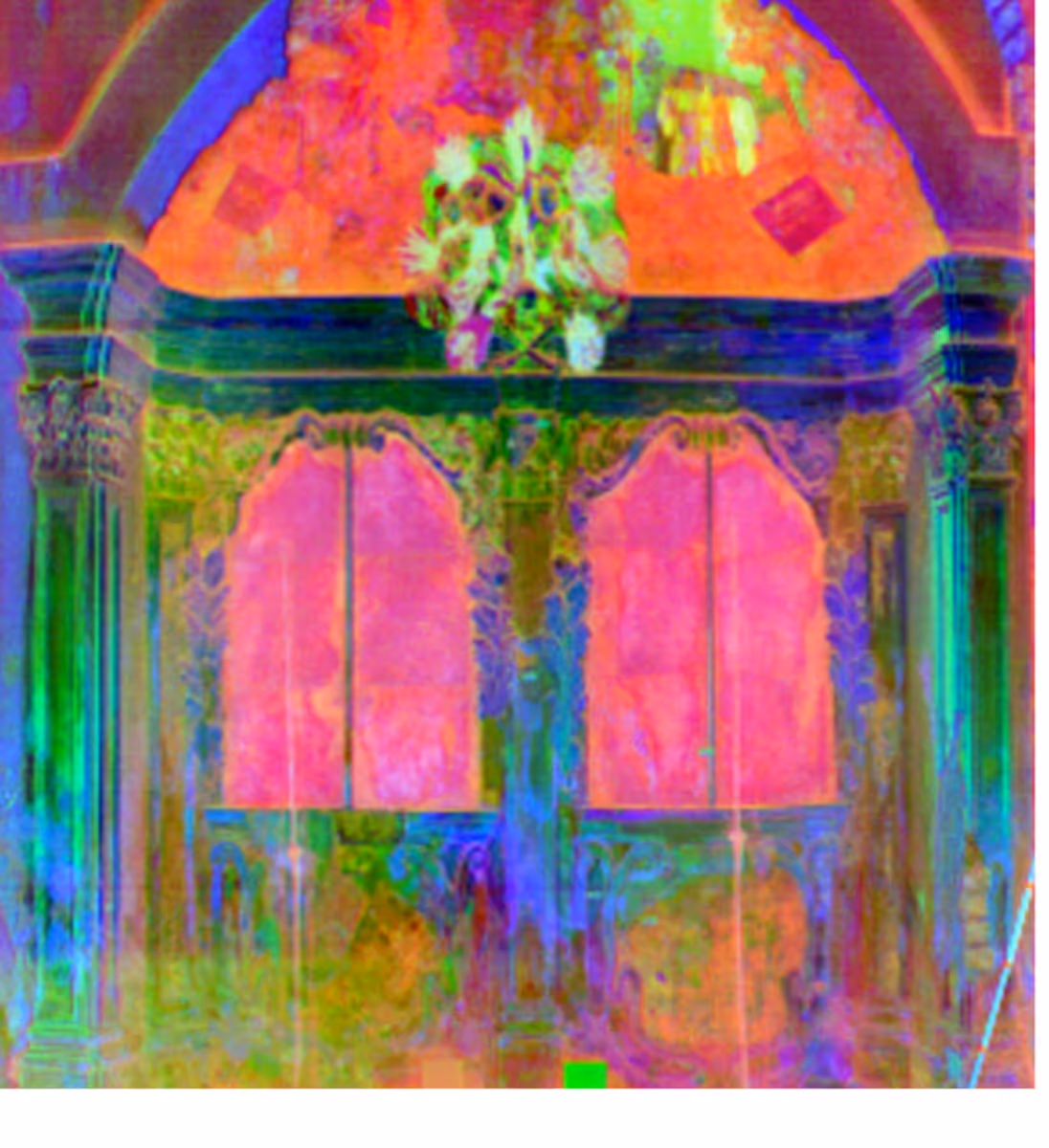 Vibrantly colored ornate interior with arched pillars, decorative panels, and a chandelier.