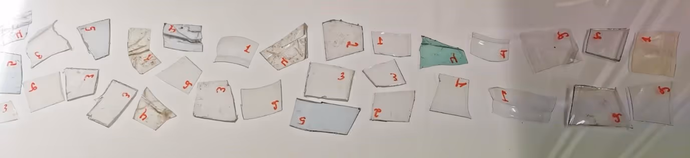 Several small, numbered broken glass shards arranged on a white surface.