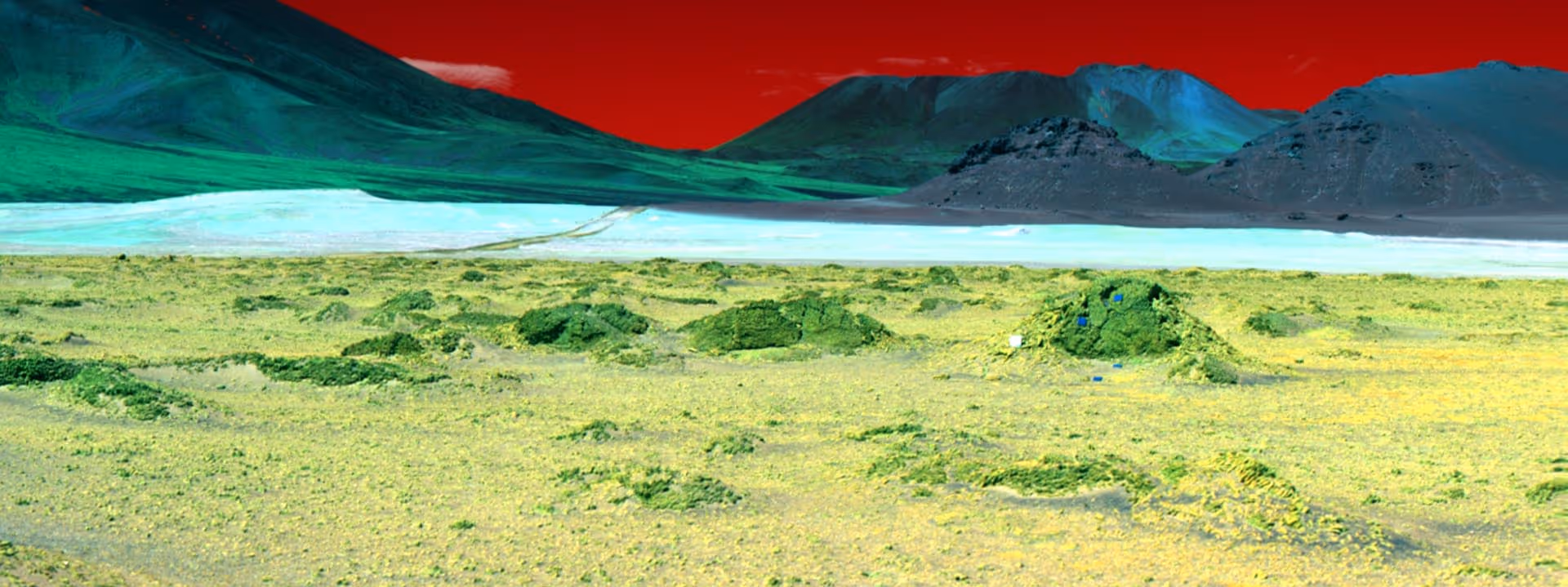 Landscape with green and yellow rocky terrain, blue and green mountains in the background, and a red sky.