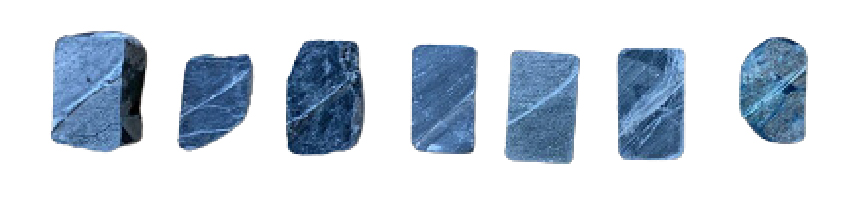 Seven rock samples with varying shapes and blue-gray striated textures arranged in a horizontal line on a white background.