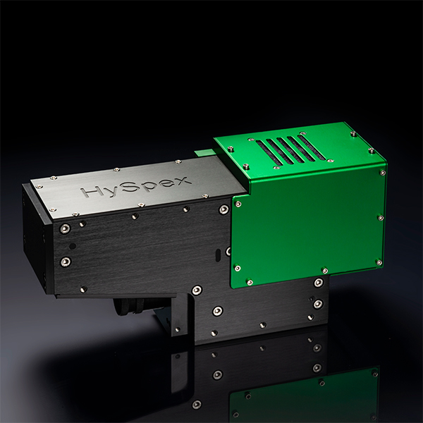 Black and green HySpex Baldur hyperspectral imaging camera on a reflective surface with a dark background.