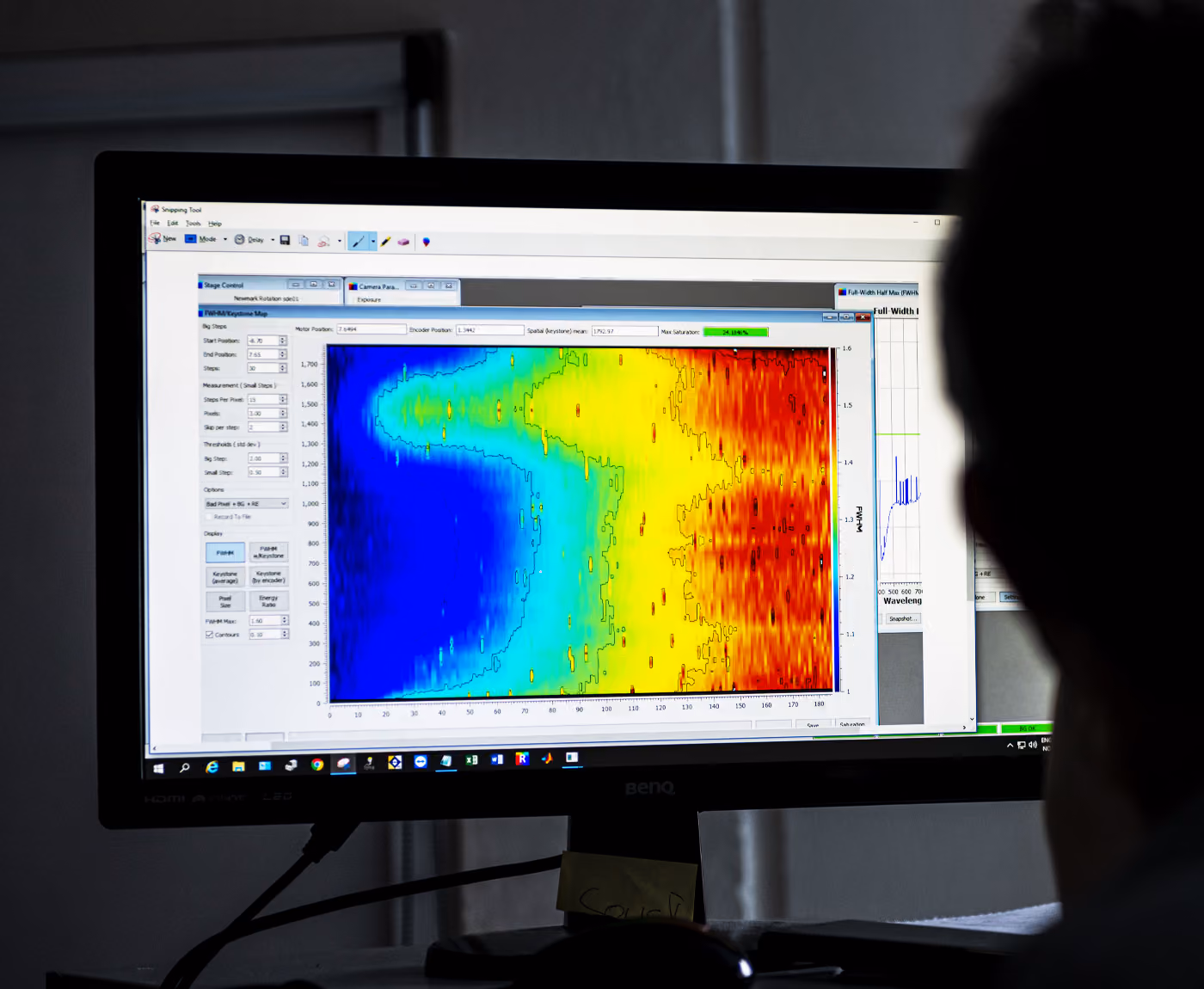 A silhouetted human sitting in front of a PC screen displaying hyperspectral data in bright colors