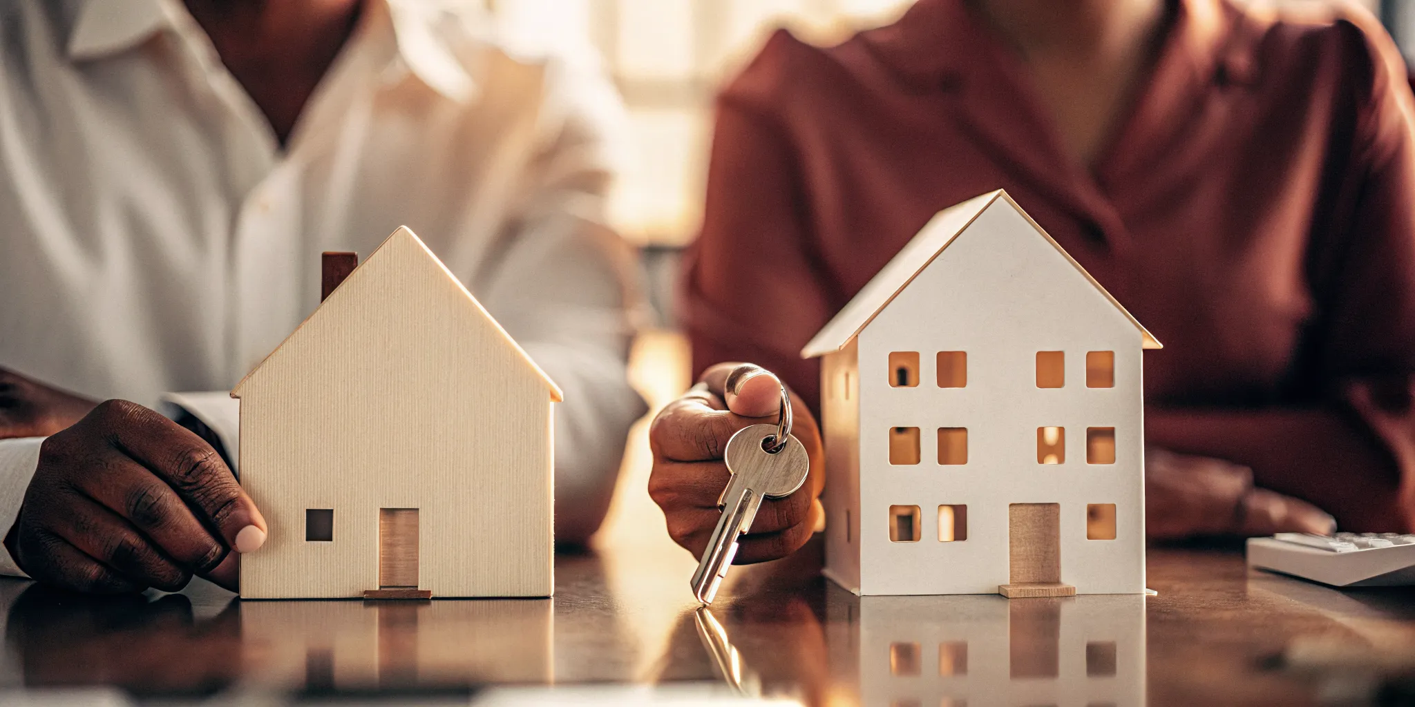 A landlord and renter with keys and a model house, discussing the Colorado PTSR.