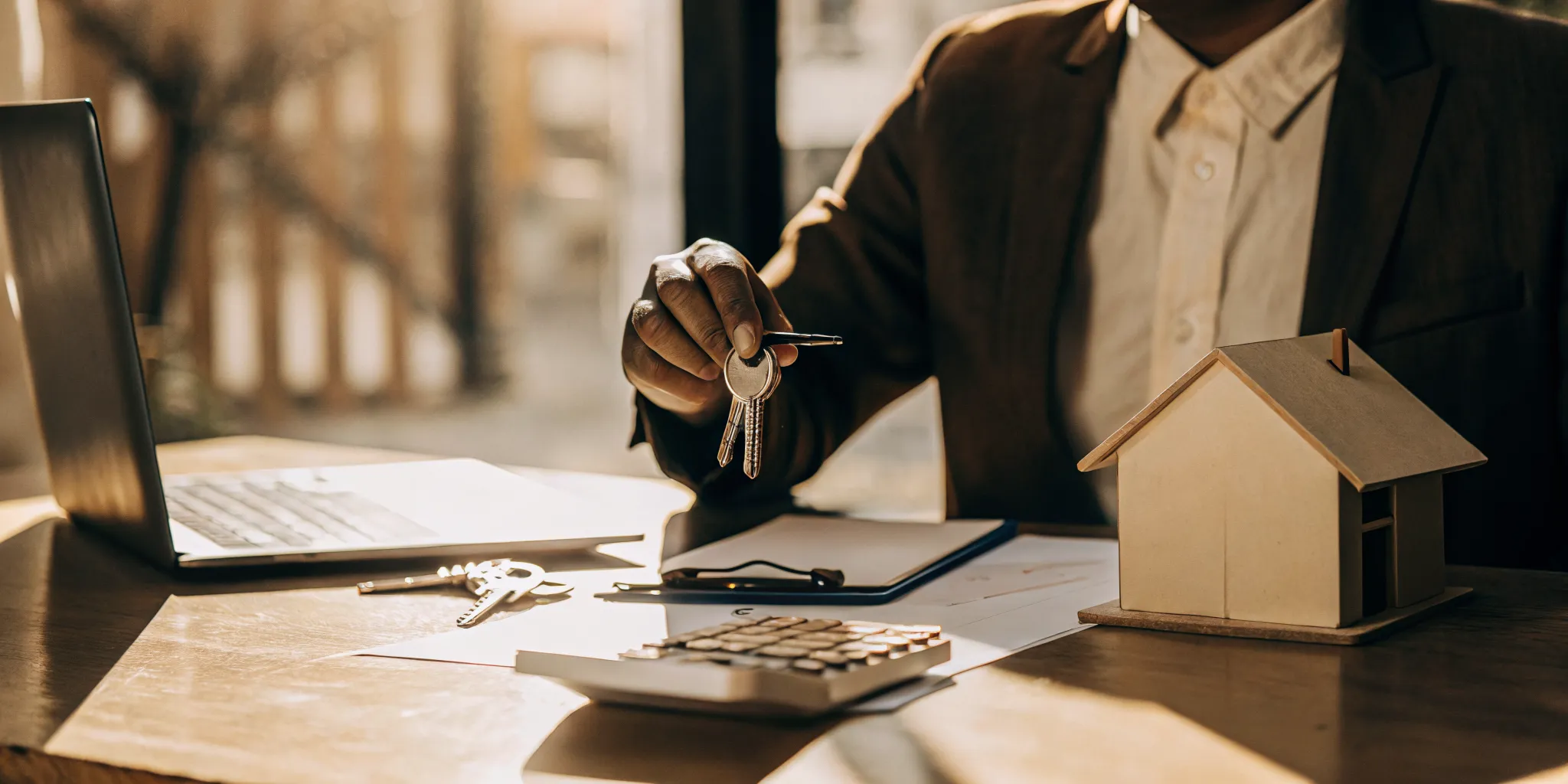 A landlord at a desk with a calculator and laptop, learning how to verify tenant income.