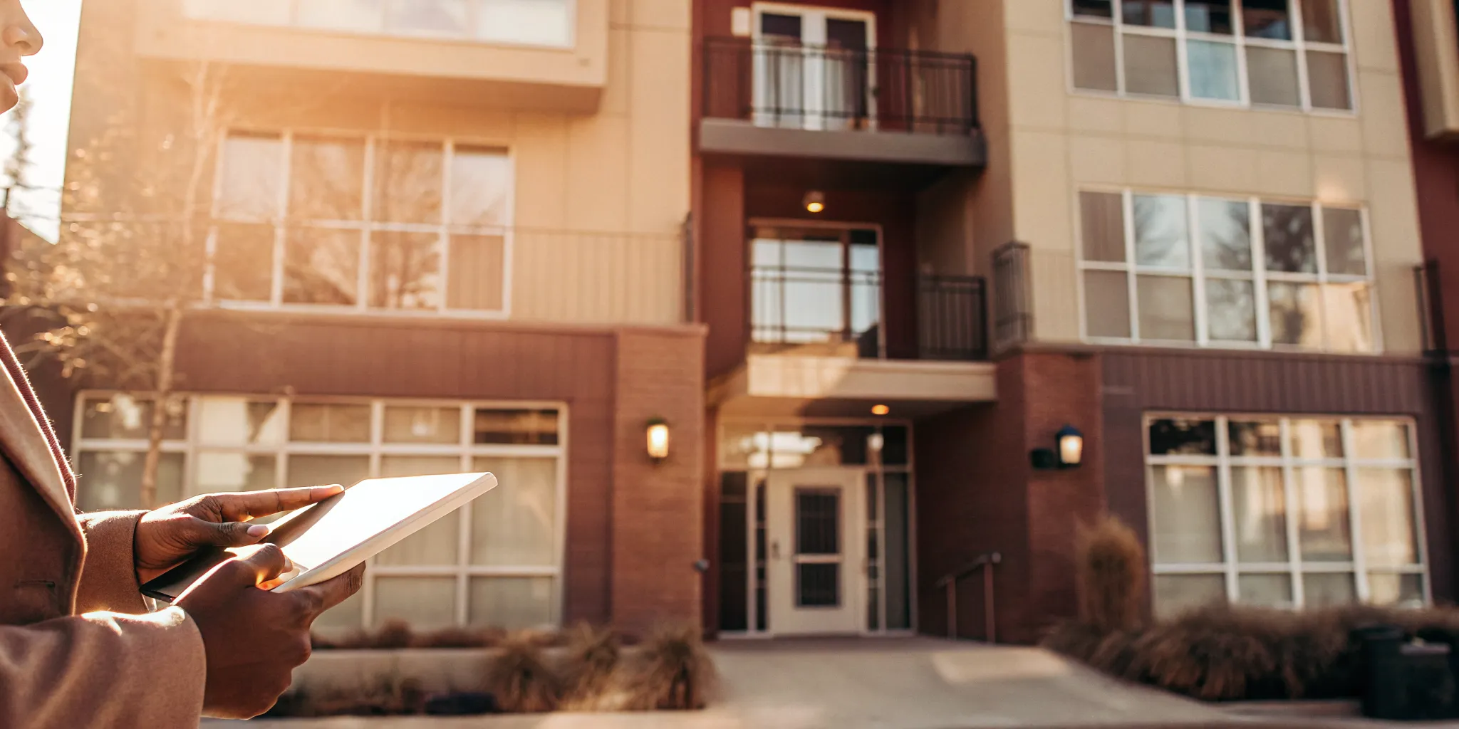 Renter holding a tablet showing a verified Portable Tenant Screening Report near a Denver apartment building
