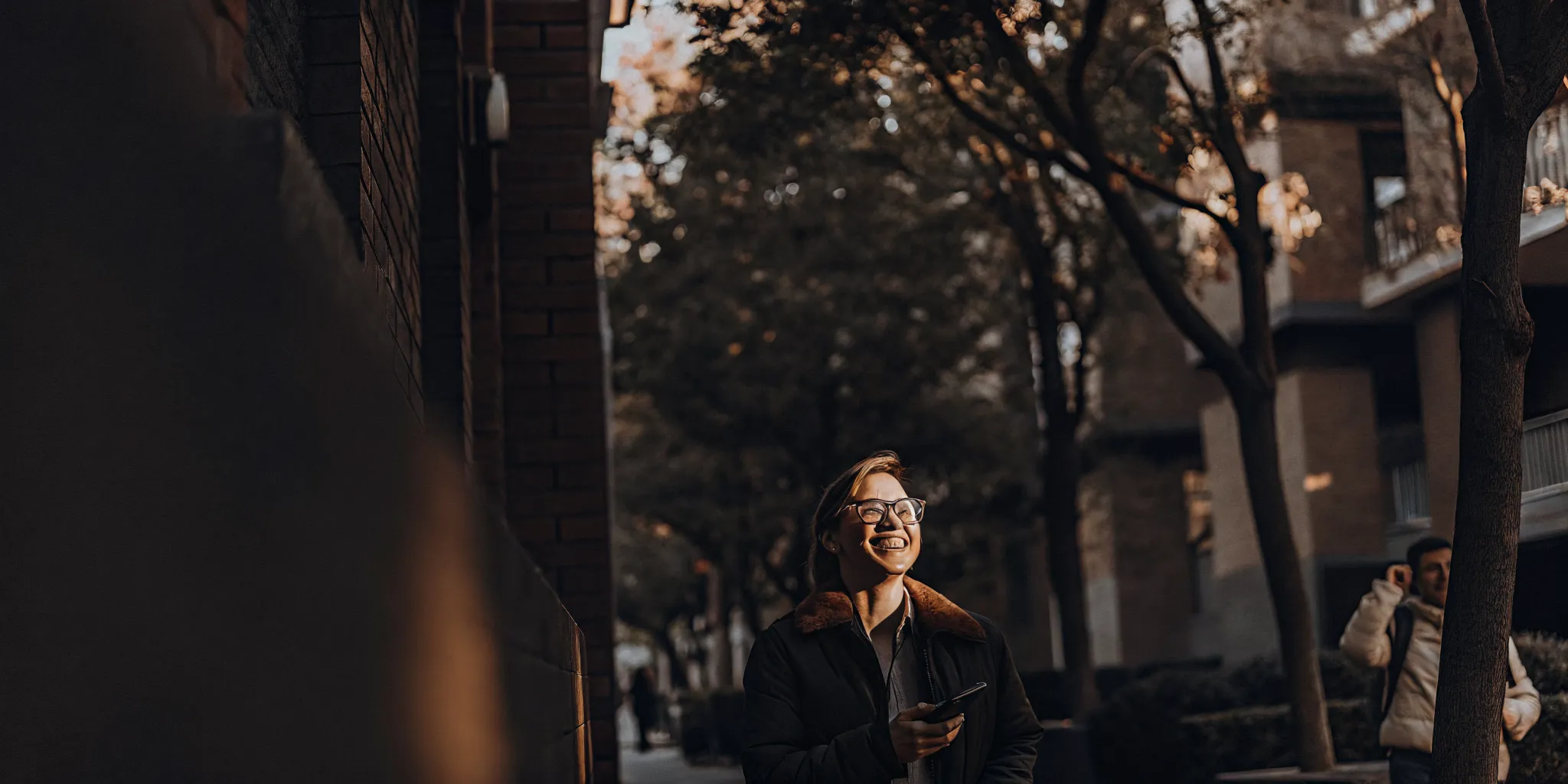 Renter holding a smartphone with a tenant screening report in front of an apartment building