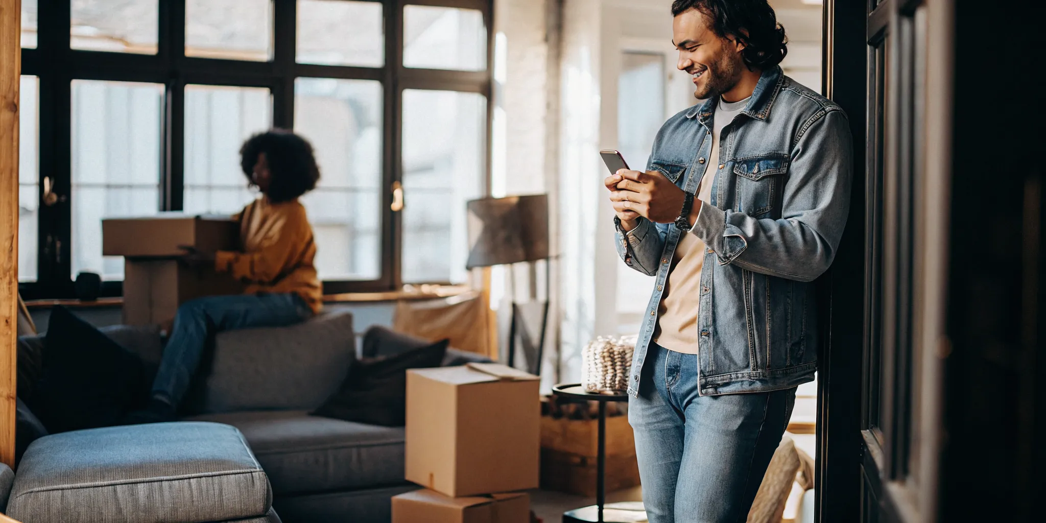 Renter checking phone with relieved expression in bright apartment