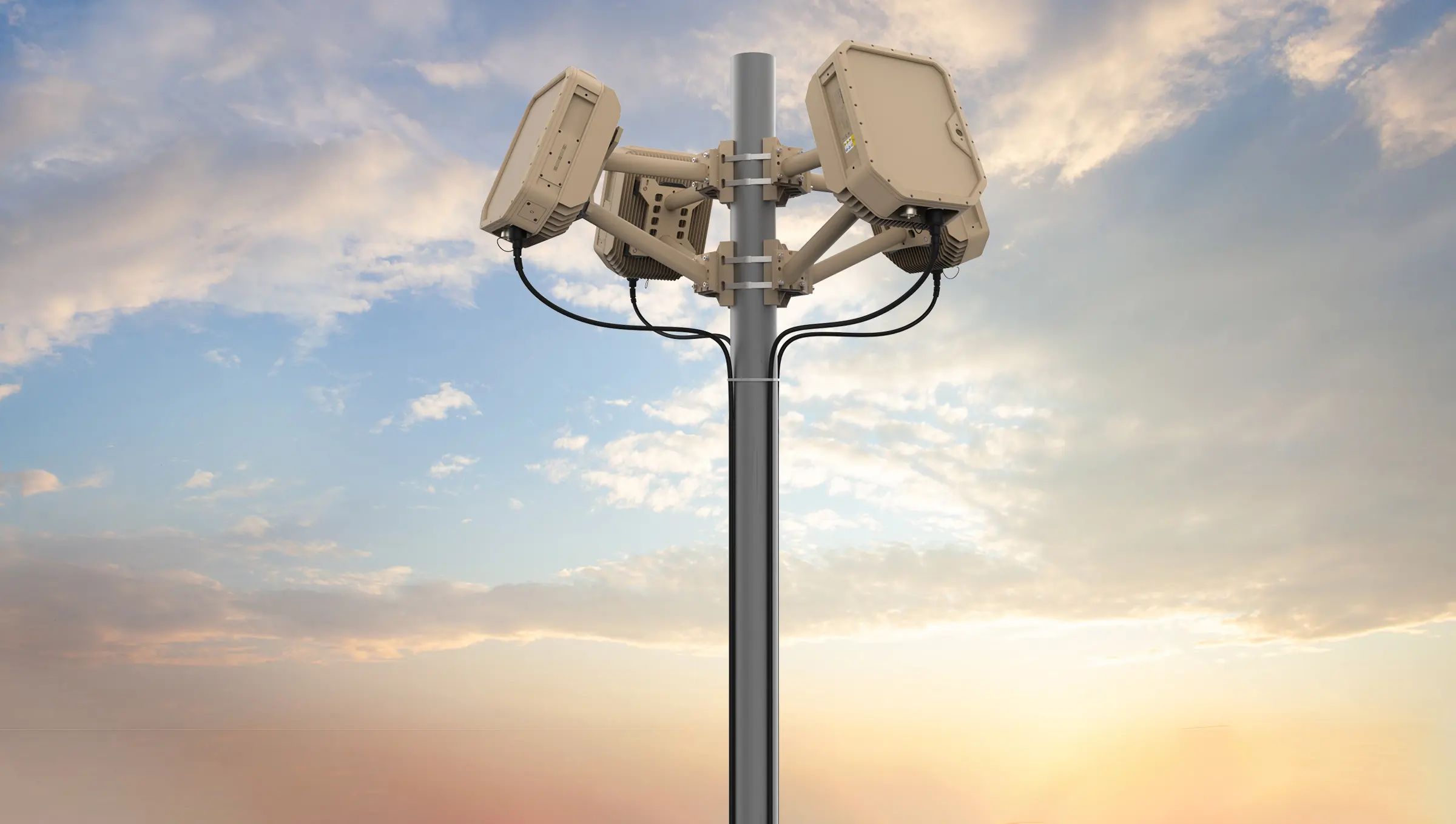 Tall gray metal pole with four beige EchoShield sensors mounted at the top against a partly cloudy sky at sunset.