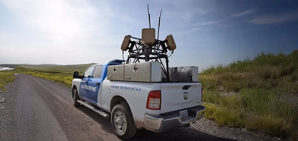 Grey vehicle with mounted EchoShield radars against a black background with grey hexagon pattern