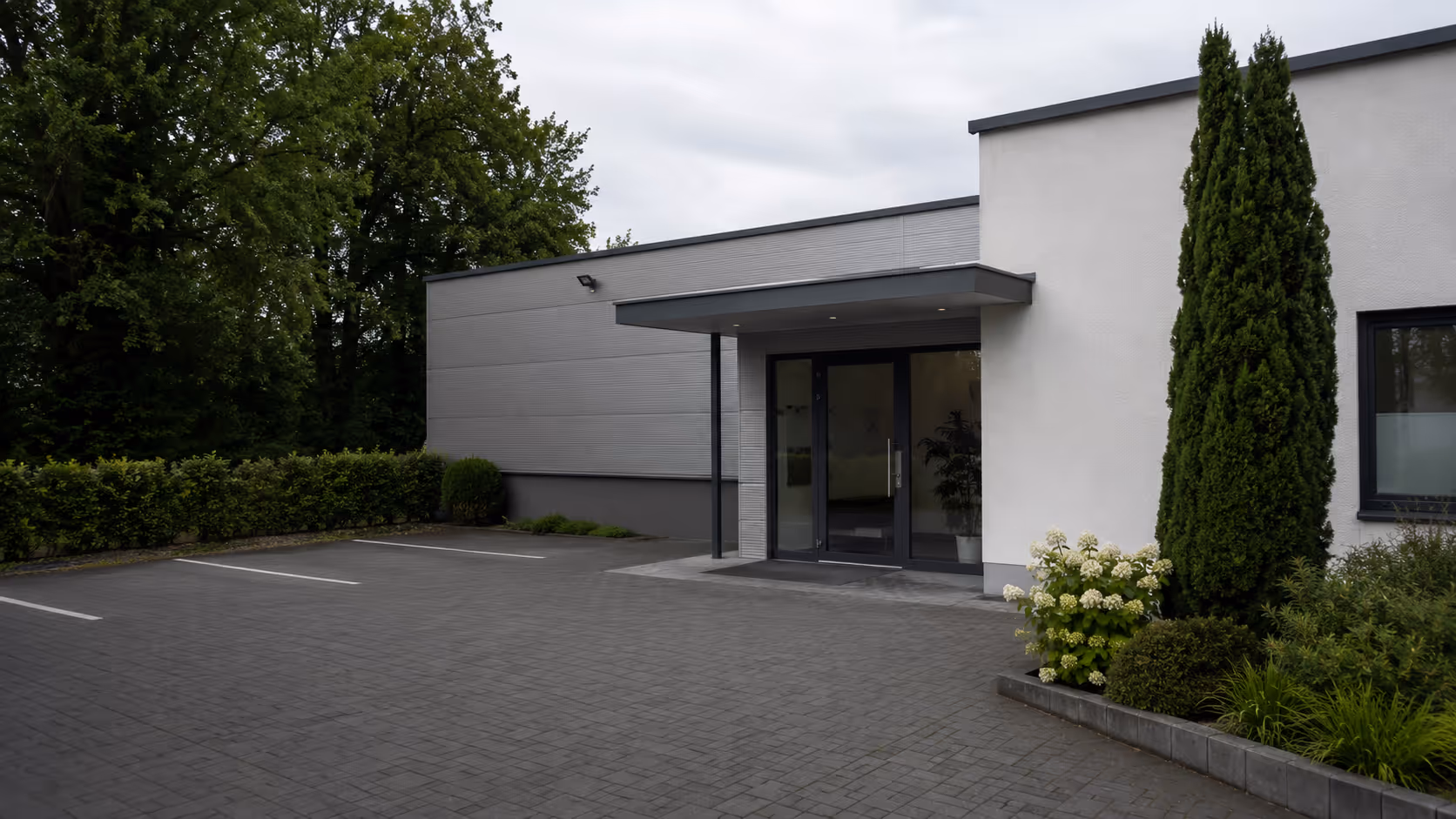 Gepflegter Eingangsbereich eines kleinen Gewerbeobjekts mit Parkplatz und sauberem Vorplatz für gewerbliche Objektbetreuung.