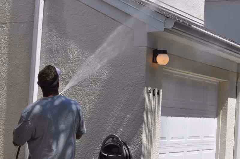 Soft wash roof cleaning equipment spraying treatment on tile roof to eliminate mold and algae growth