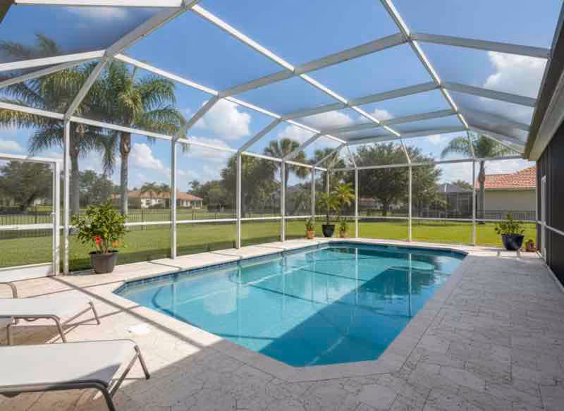 Technician performing screen enclosure cleaning on residential pool cage eliminating mold and mildew