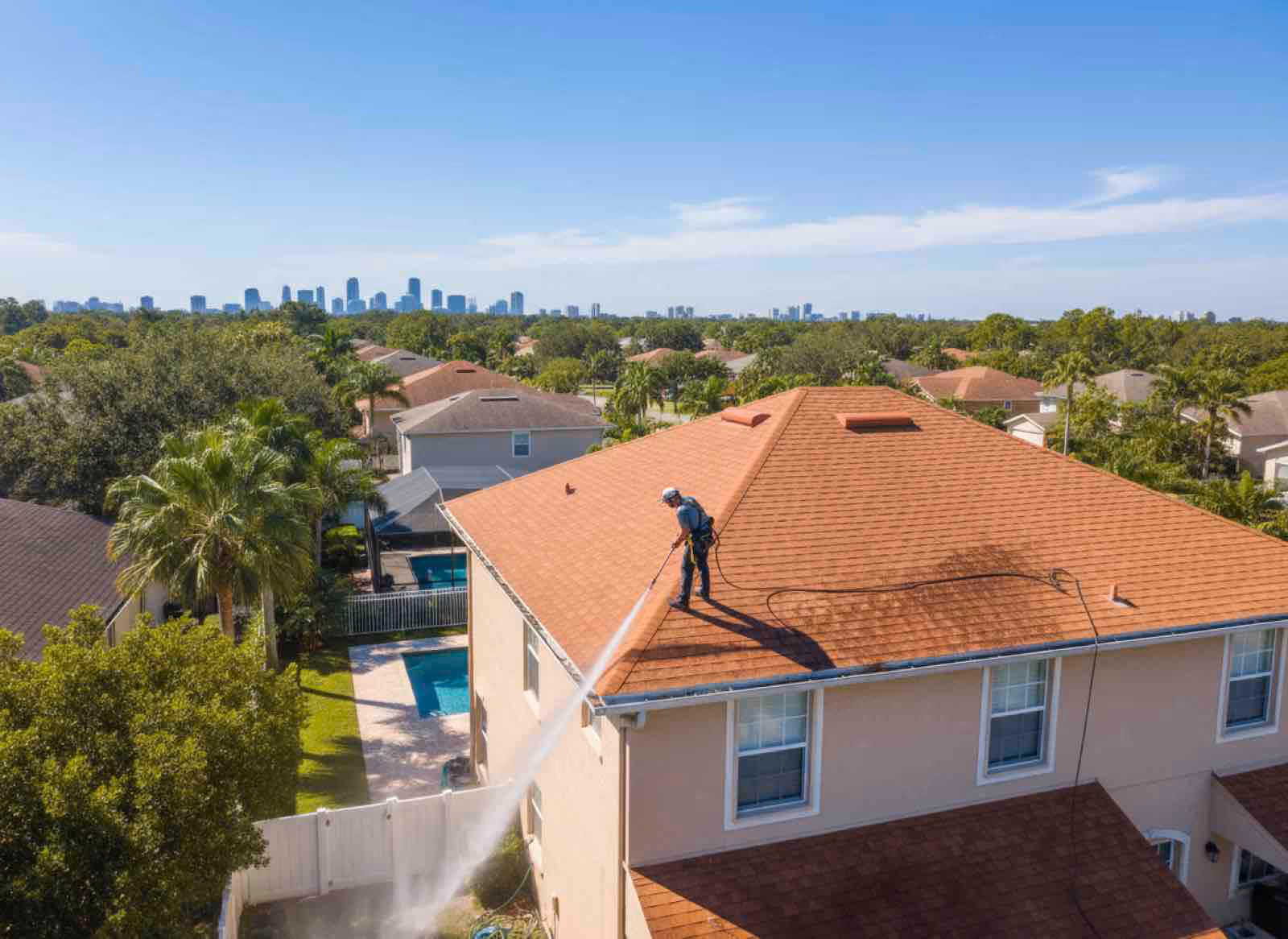 Technician pressure washing gutters on residential home to restore original color and eliminate tiger striping