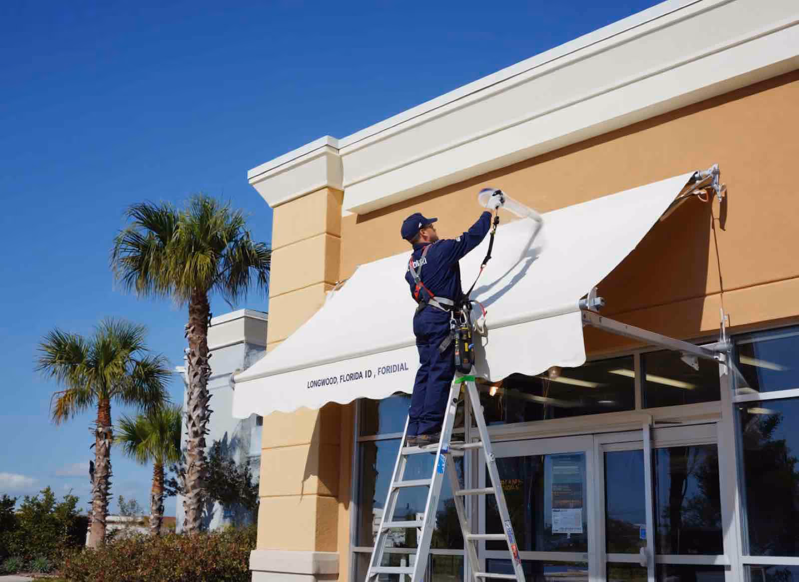 Awning cleaning specialist treating striped canvas with low-pressure cleaning at Spring Oaks home
