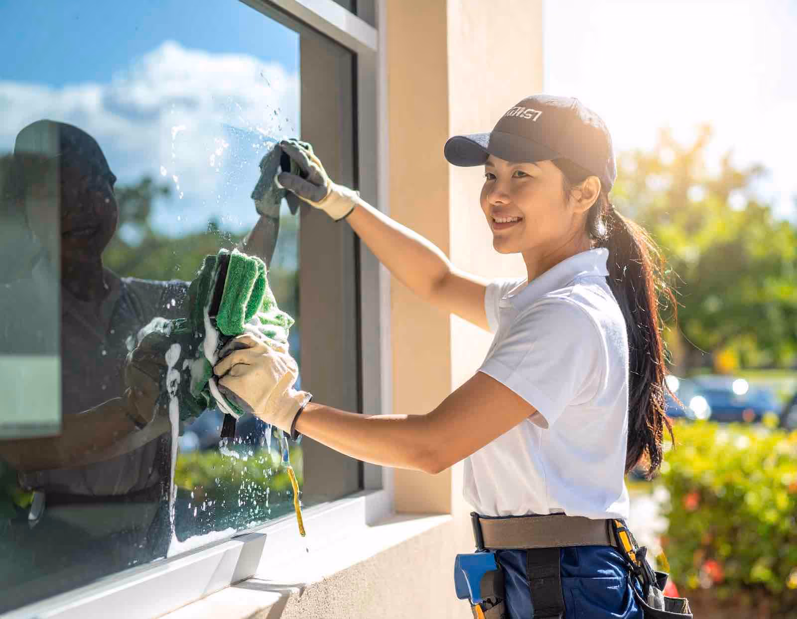 Professional commercial window cleaning technician using purified water system on retail storefront windows