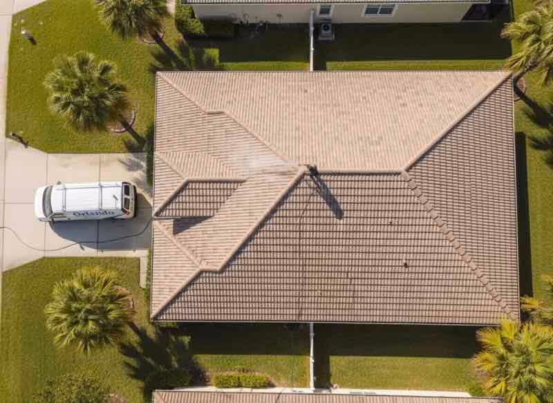 Professional soft washing service removing dark algae and moss stains from asphalt shingle roof in Longwood, Florida