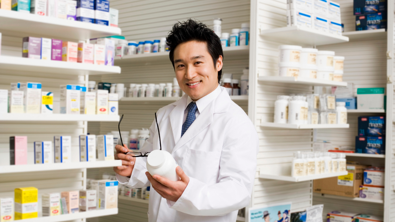 Médecin souriante avec une blouse blanche et un stéthoscope violet parlant avec un patient dans un cabinet médical.