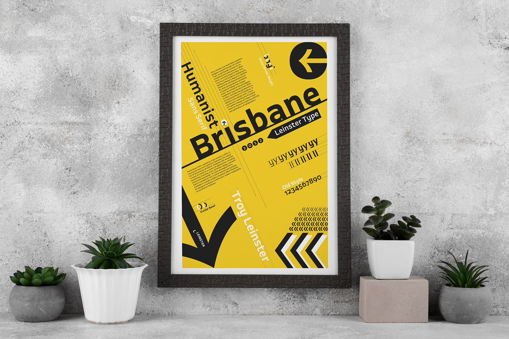 Black framed poster with yellow background displaying typographic elements and text samples for 'Brisbane' in various styles, leaning against a textured concrete wall surrounded by four small potted plants.
