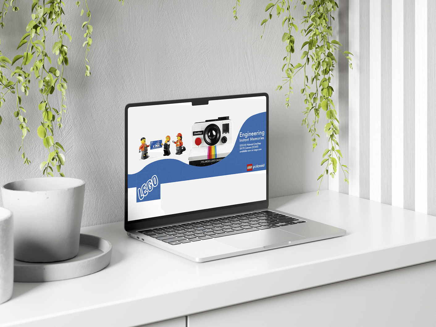 Silver laptop on white desk displaying a LEGO Polaroid OneStep camera product page with LEGO minifigures and product details.