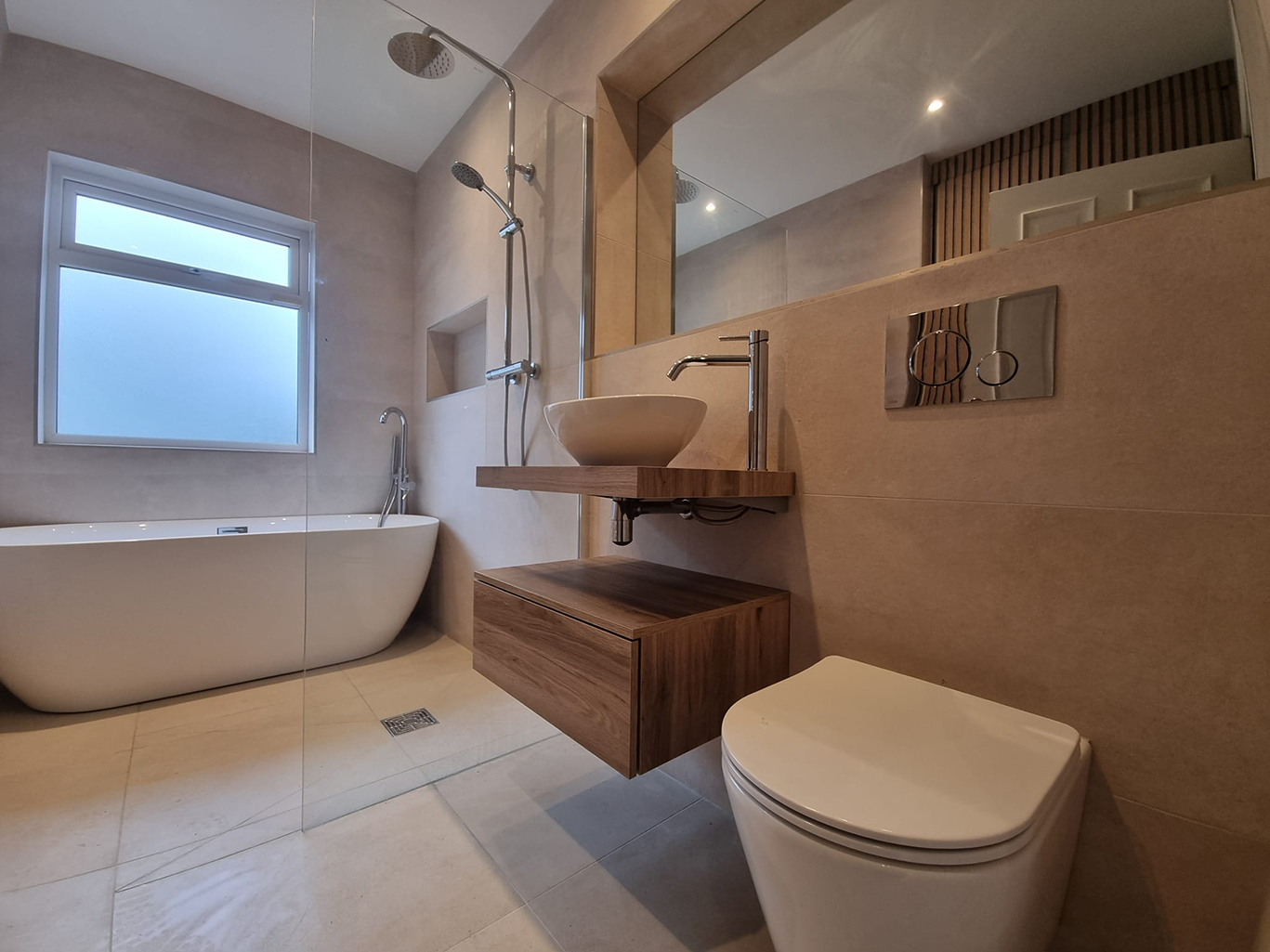 Modern bathroom with a freestanding white bathtub, walk-in shower, wall-mounted sink with wooden shelf, and a white toilet.