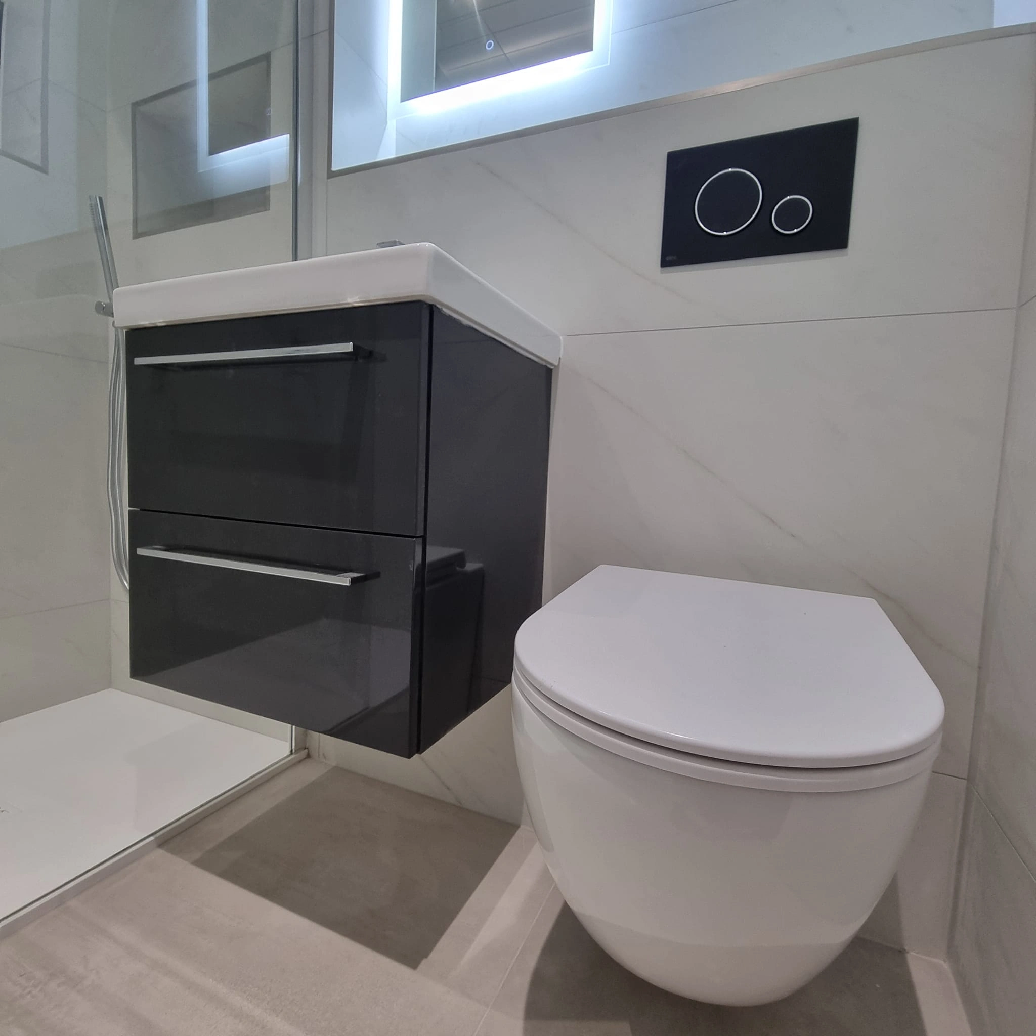 Modern bathroom with a wall-mounted toilet and a floating black vanity with a white countertop.