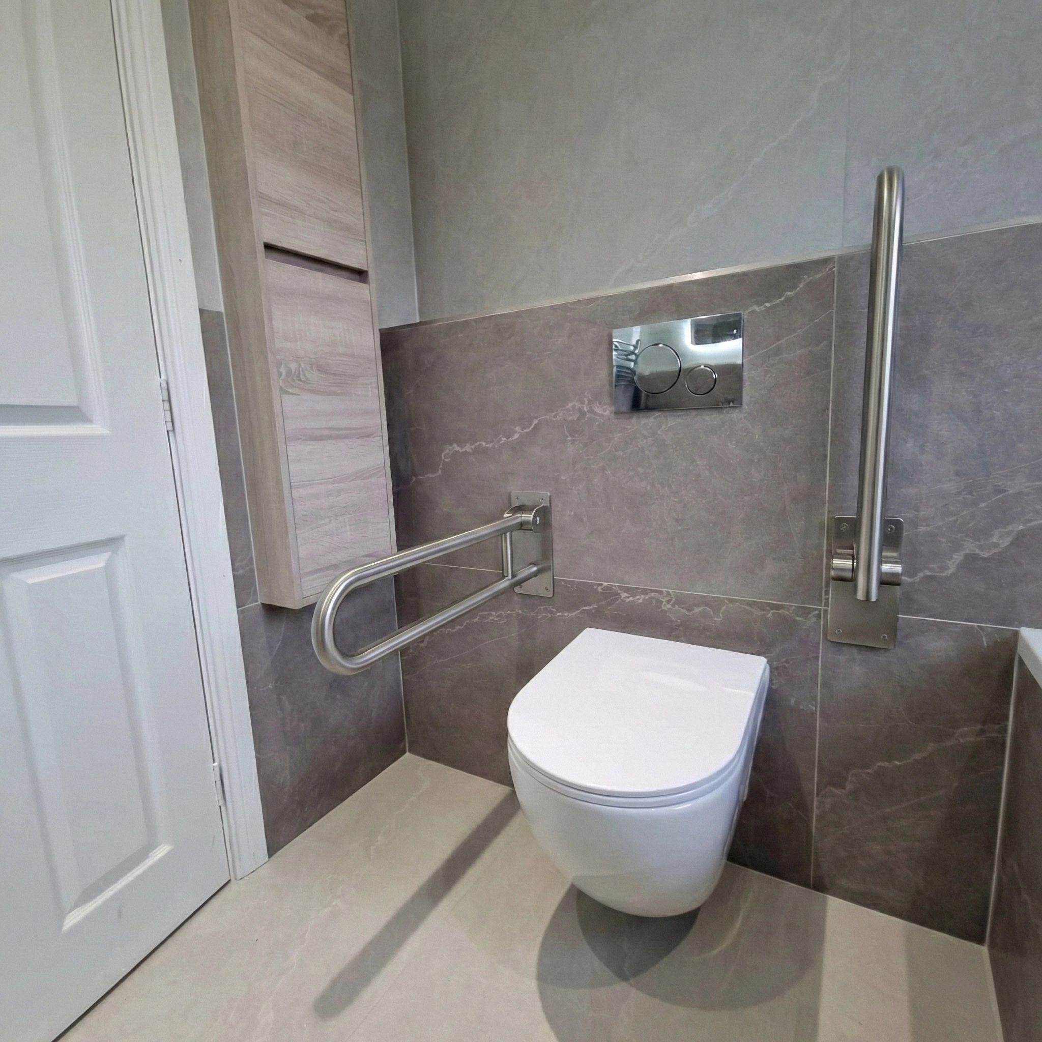Modern accessible bathroom with wall-mounted toilet and stainless steel grab bars on both sides.