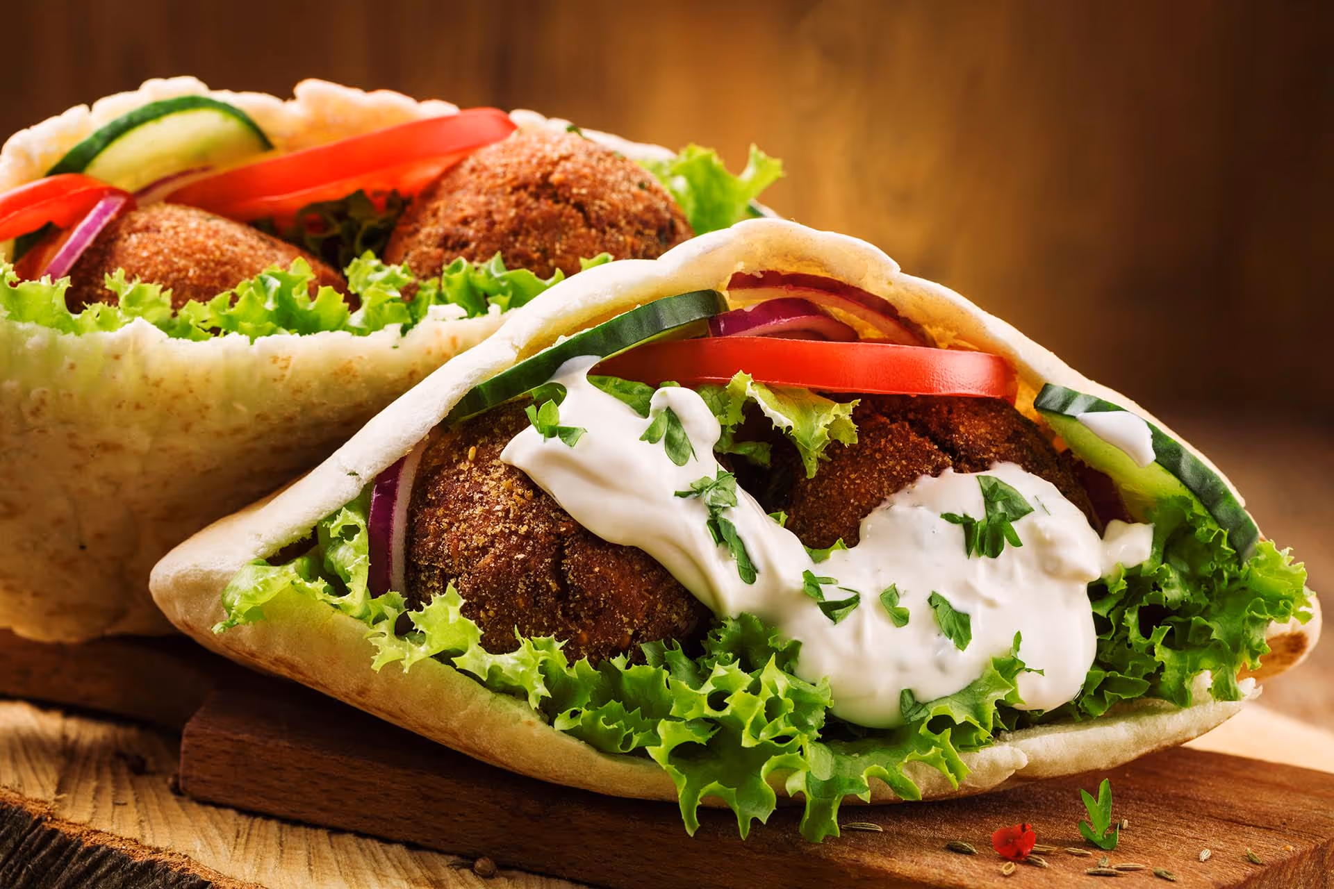 A sandwich with meatballs and lettuce on a wooden table.