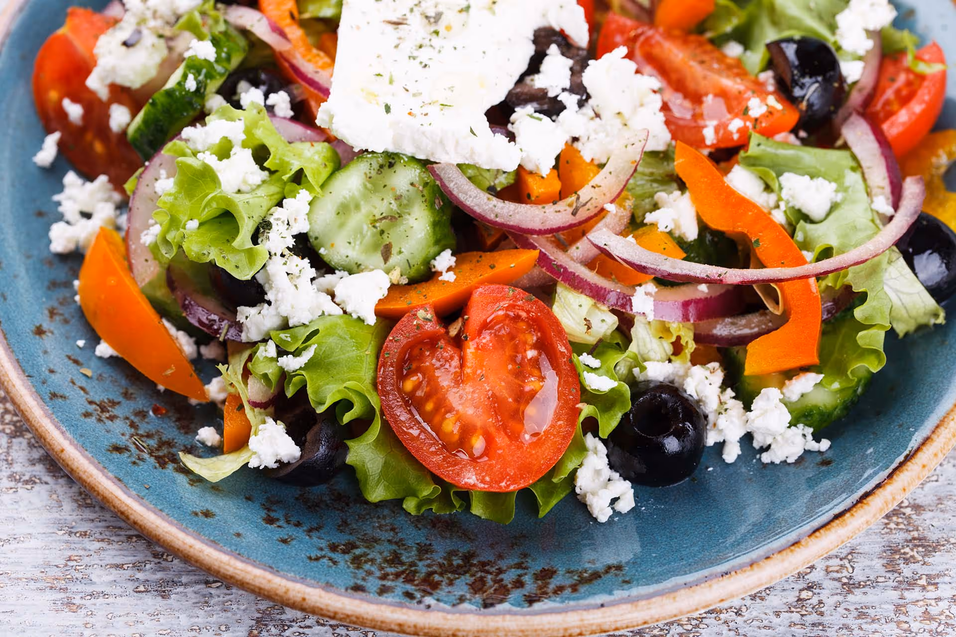 A plate of salad with tomatoes, cucumbers, and feta cheese.