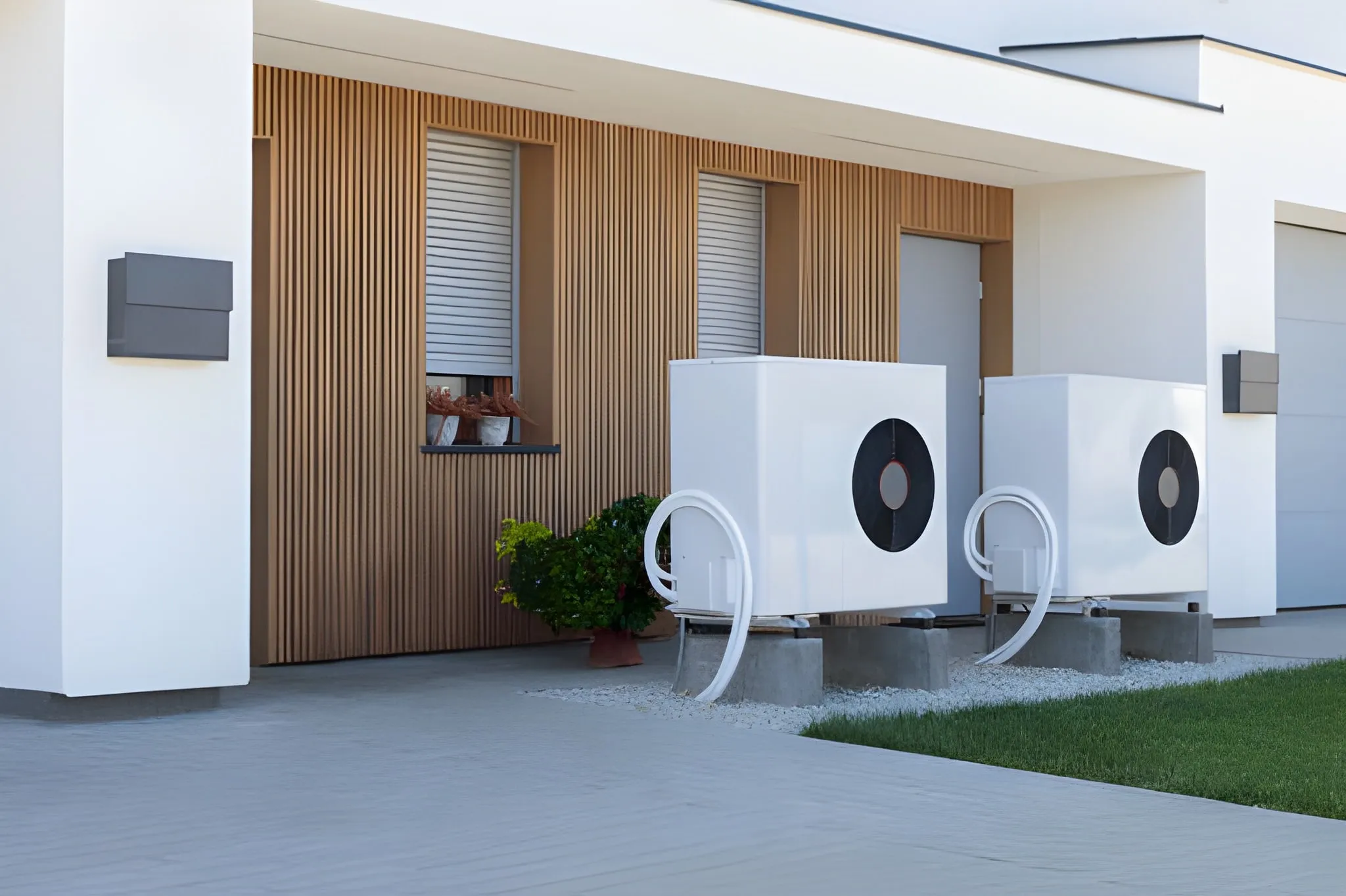 Modern house exterior with wood siding, two white heat pump units with white ducts