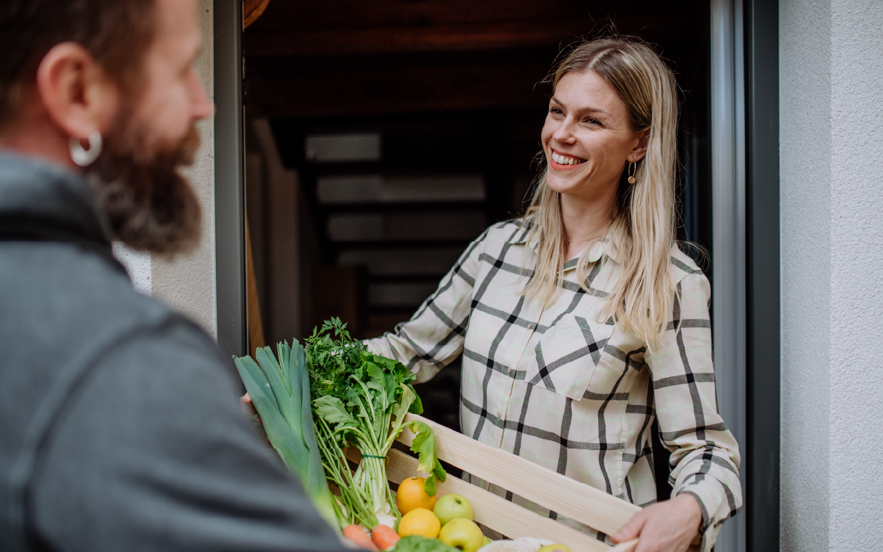 Woman delivering fresh groceries to a doorstep, showing friendly and local delivery assistance.