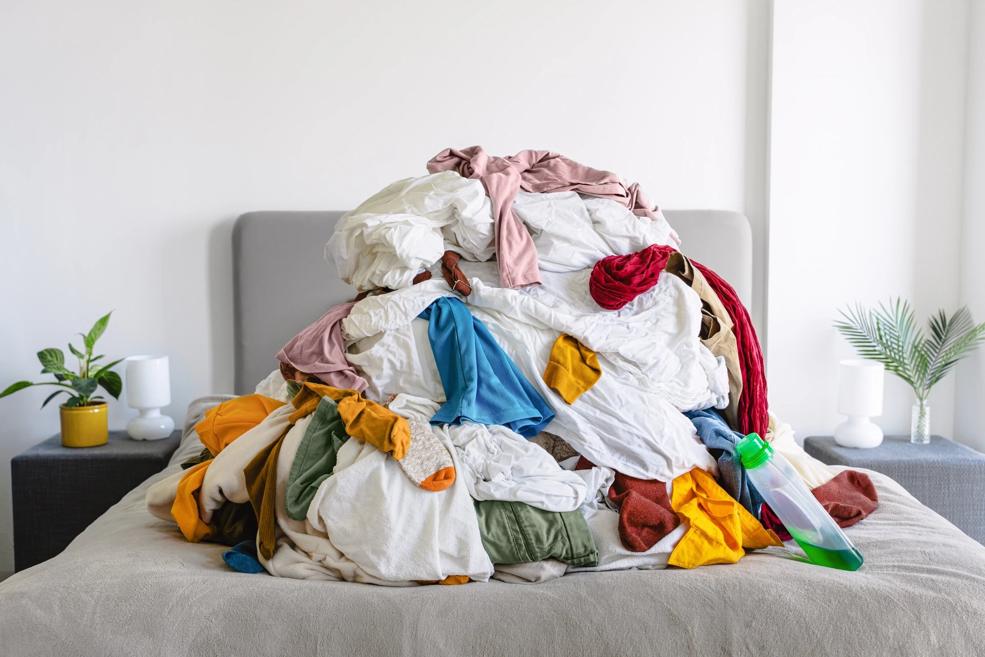 A colorful pile of laundry on a bed representing everyday household chores — used as a background for Lucky Services’ Montrose call-to-action section.