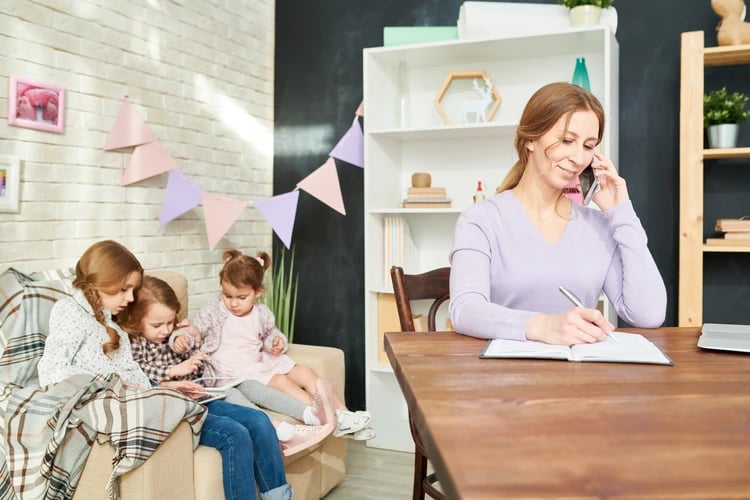 A busy parent on the phone while children play nearby, symbolizing Lucky Services helping Ouray families manage household tasks and find more free time.