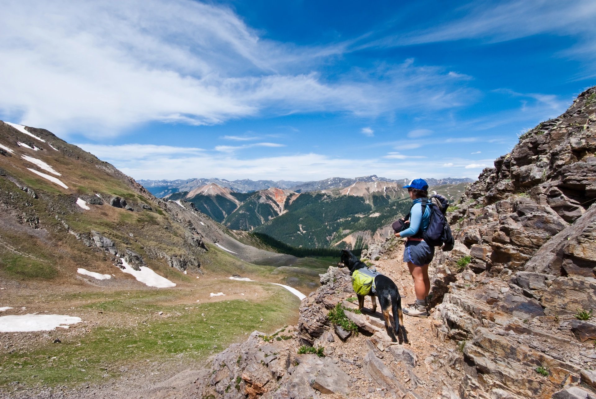 A hiker with a dog enjoying mountain views near Ridgway, Colorado, symbolizing the freedom and time Lucky Services gives back to local residents.