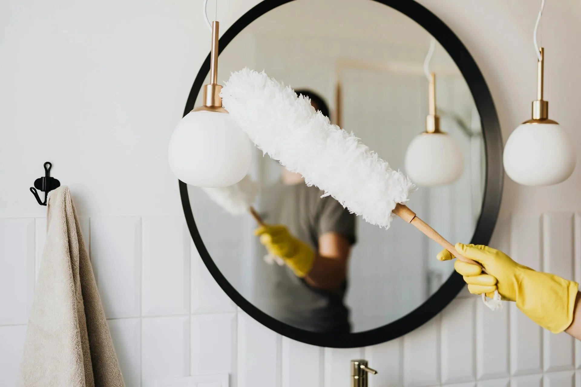 Close-up of a Lucky Services cleaner dusting a light fixture in a modern Santa Fe home, symbolizing professional house cleaning and attention to detail.