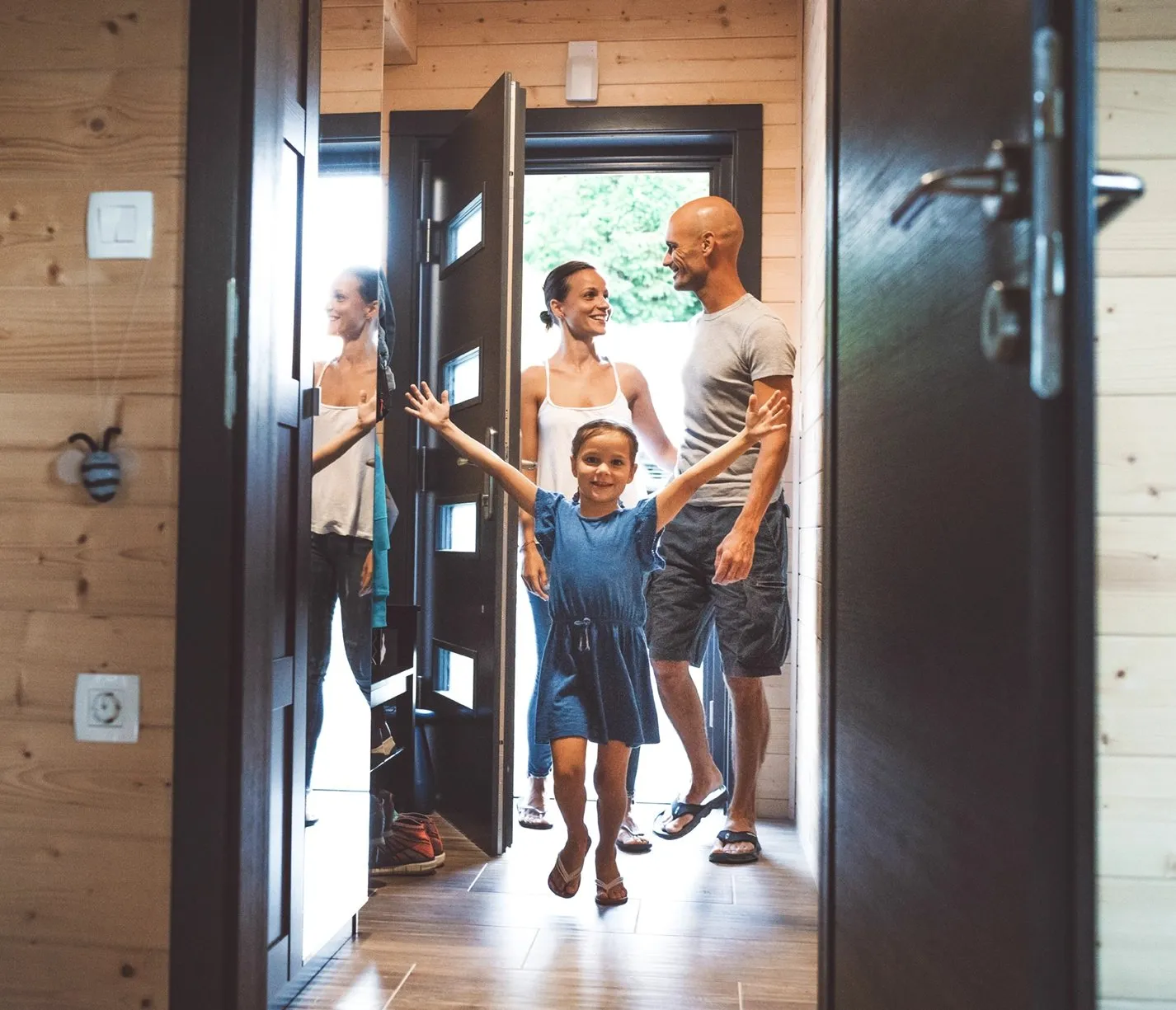 Excited family being welcomed into their vacation rental, with a young girl running toward the door.