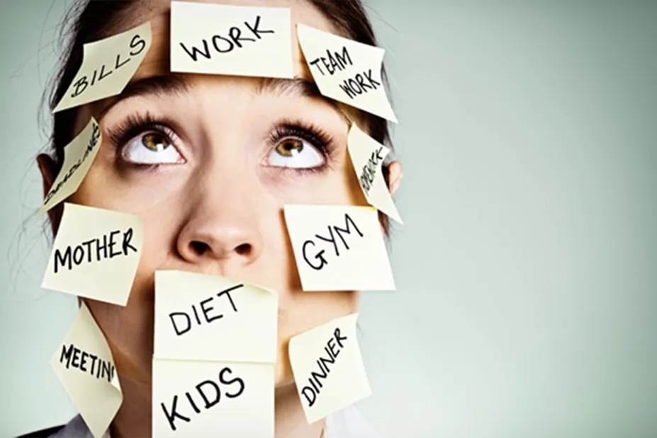 Overwhelmed woman covered in sticky notes labeled with tasks like bills, work, gym, and kids, symbolizing an overloaded to-do list.