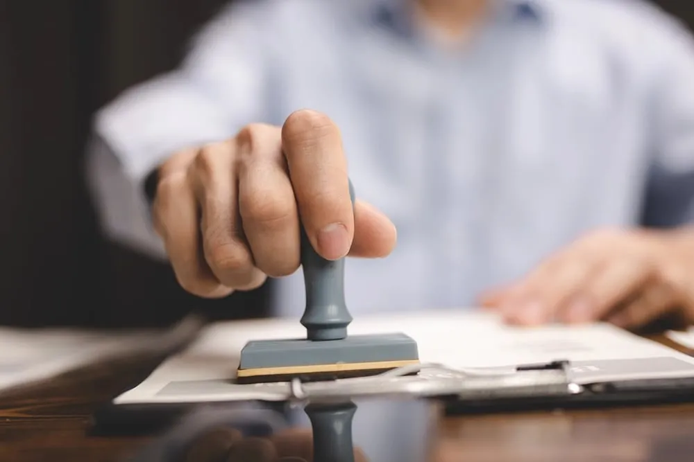 Close-up of a hand stamping a document with an official notary seal.