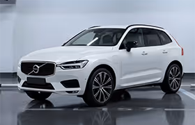 White Volvo XC40 compact SUV parked indoors with a reflective floor and plain background.