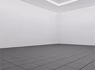 Empty gray tiled room with white walls and a ceiling corner.