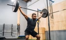 Man performing a heavy barbell lift during a CrossFit workout